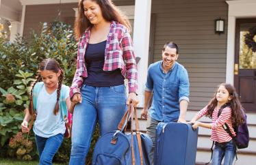 family of four walking away from their home to go on vacation