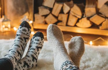 close up of two homeowners' feet wearing socks and resting on a cozy rug in front of a fireplace