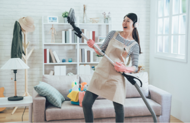happy homeowner listening to music and holding up a vacuum