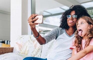Woman and child sit on the couch taking a selfie. 