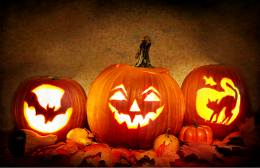 three pumpkins with varying designs with lights inside