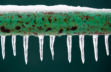 green pipe with icicles hanging from the bottom