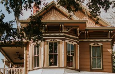 Photo of an older home with a bay window and a patio on the side