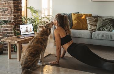 Image of female doing yoga in front of laptop with dog