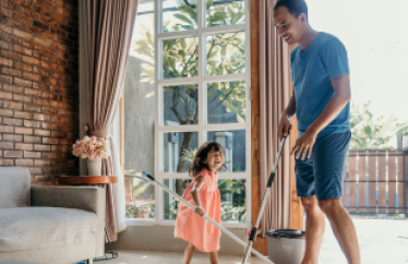 father and daughter cleaning living room together