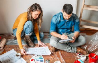 couple looking at plans on the floor of their home and preparing for home upgrades