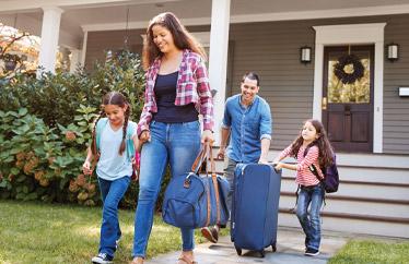 family of four walking away from their home to go on vacation
