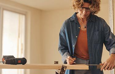 homeowner measuring a piece of wood to prepare for a DIY project