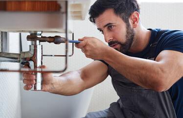 homeowner tightening pipes under bathroom sink